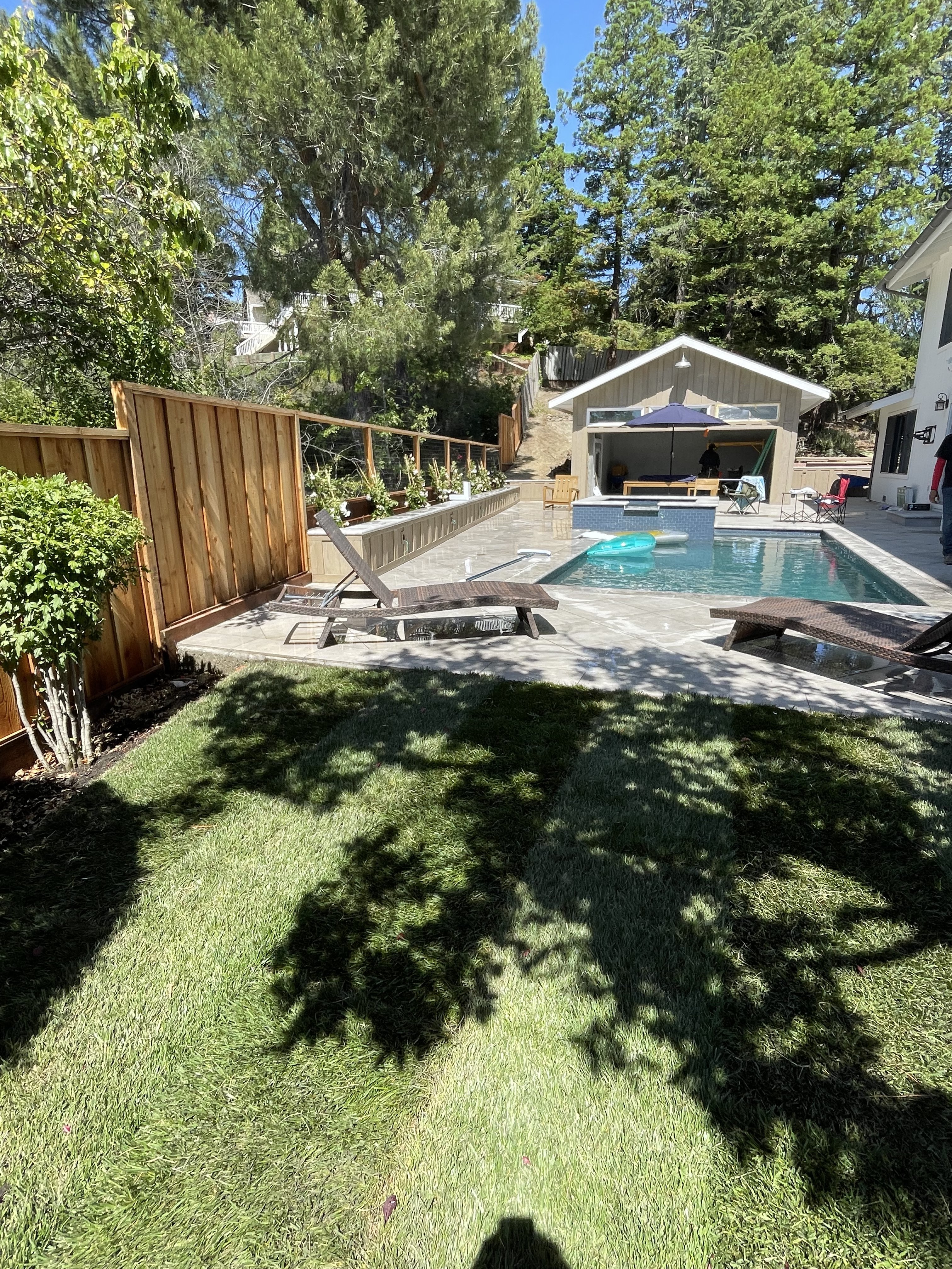 Completed backyard pool with artificial turf and pool house by BlackHawk Landscaping